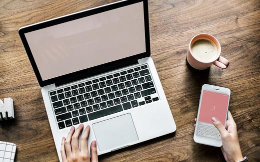 Aerial view of woman using computer laptop and a smartphone on wooden table