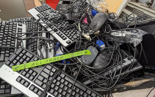 Various keyboards and computer mice stacked haphazardly to be disposed of as electronic waste