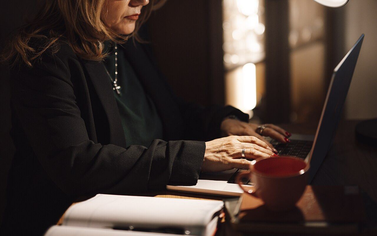 A woman is focused on her laptop while typing in her home office